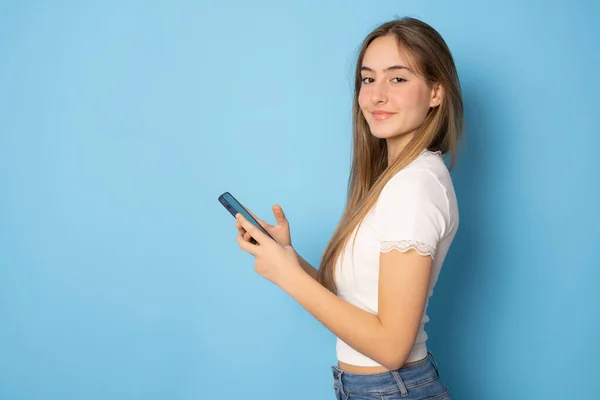 Beautiful Girl Using Smartphone Standing Isolated Blue Background — Stockfoto