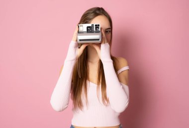 Beautiful girl with photo camera with thumb up isolated over pink background.