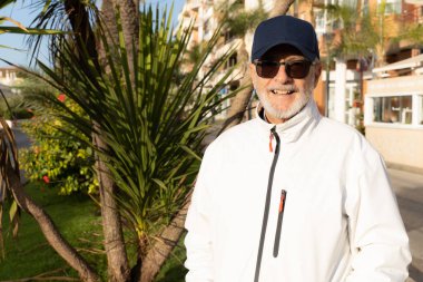 Senior smiling man wearing cap outdoors in the city.