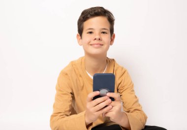 Beyaz arka planda izole edilmiş akıllı telefon kullanan günlük kıyafetli beyaz çocuk..