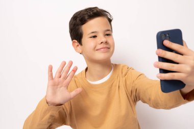 Beyaz arka planda izole edilmiş akıllı telefon kullanan günlük kıyafetli beyaz çocuk..