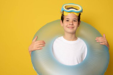 Şişirilebilir yüzüklü ve sarı arka planda dalış gözlüklü tatlı çocuk.