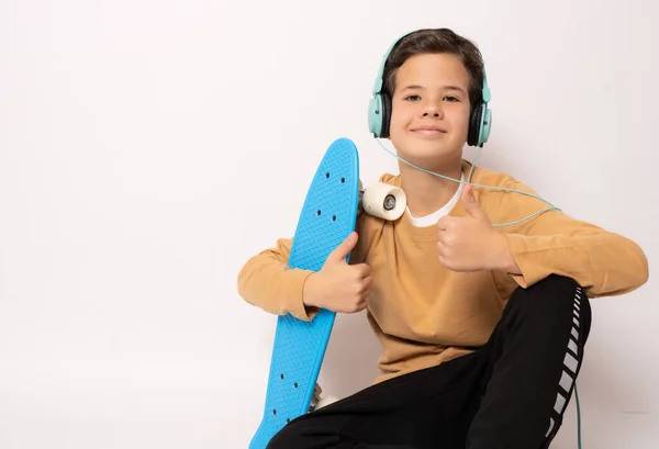 Söt Pojke Bär Hörlurar Med Skateboard Visar Tummen Upp Isolerad — Stockfoto