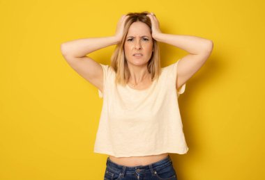 Kızgın kadın sarı arka planda tek başına saçını çekiyor..