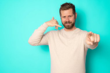 Genç sakallı adam yeşil arka planda tek başına dururken bana jest diyor..