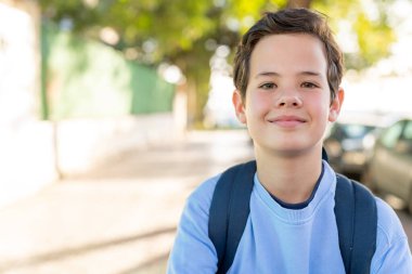 Okul dışında sırt çantalı sevimli bir çocuğun portresini çek..