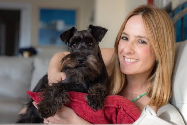 Evinde sevimli schnauzer 'ıyla gülümseyen genç bir kadının portresini yakından çek. Hayvan iletişim konsepti