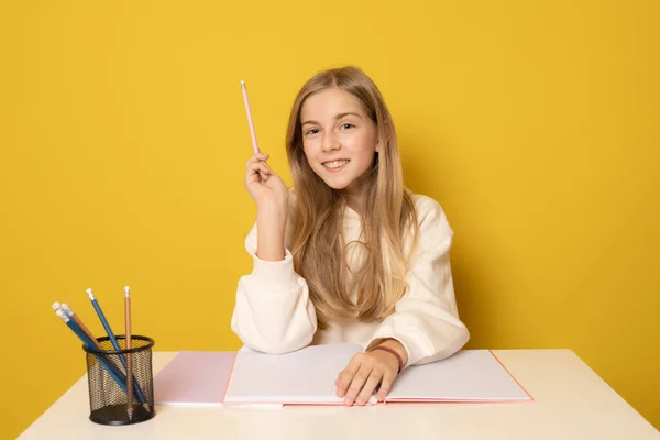 Hermosa Chica Sonriente Sentada Mesa Escribiendo Cuaderno Sobre Fondo Amarillo —  Fotos de Stock