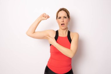 Güzel bir fitness kadınının portresi beyaz arka planda izole edilmiş pazılarını gösteriyor.
