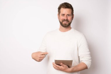 Sıradan kıyafetler giyen, tablet kullanan, beyaz arka planda izole edilmiş genç bir adam. İş konsepti.