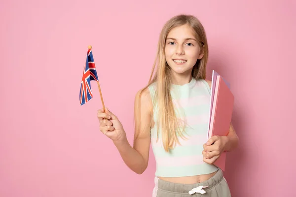 年轻美丽的姑娘举着英国国旗 孤零零地站在粉红的背景上 教育概念 — 图库照片