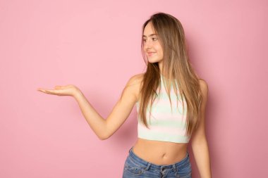 Neşeli genç kız, mutlu gülümseme, ürün tanıtımı, pembe renkli arka planda izole edilmiş reklam.