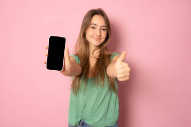 Boş cep telefonu ekranı gösteren ve memnun görünen şık bir kız, akıllı telefon için tavsiye edilen bir uygulama, pembe arka planda alışveriş sitesi gösterimi