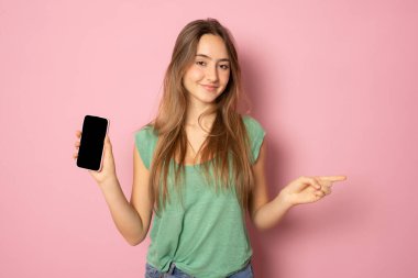 Boş cep telefonu ekranı gösteren ve memnun görünen şık bir kız, akıllı telefon için tavsiye edilen bir uygulama, pembe arka planda alışveriş sitesi gösterimi