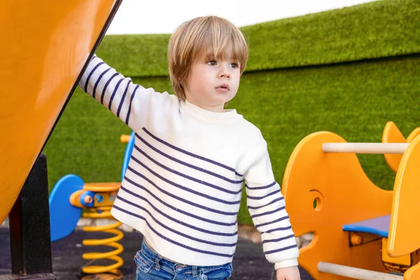 Üç yaşındaki bir çocuk okuldan sonra parkta oyun oynarken eğleniyor.