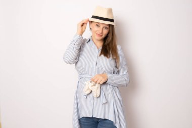 Neşeli ve hamile bir kadın küçük bebek botları tutuyor.