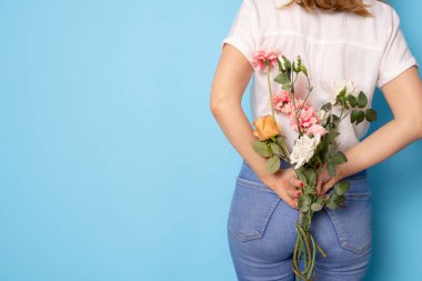 Arka plan, çiçek tutan genç bayan bahar tatilini mavi arka planda yalnız kutluyor.