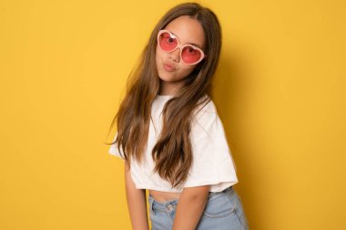 Sarı arka planda güneş gözlüğü takan güzel esmer kız..