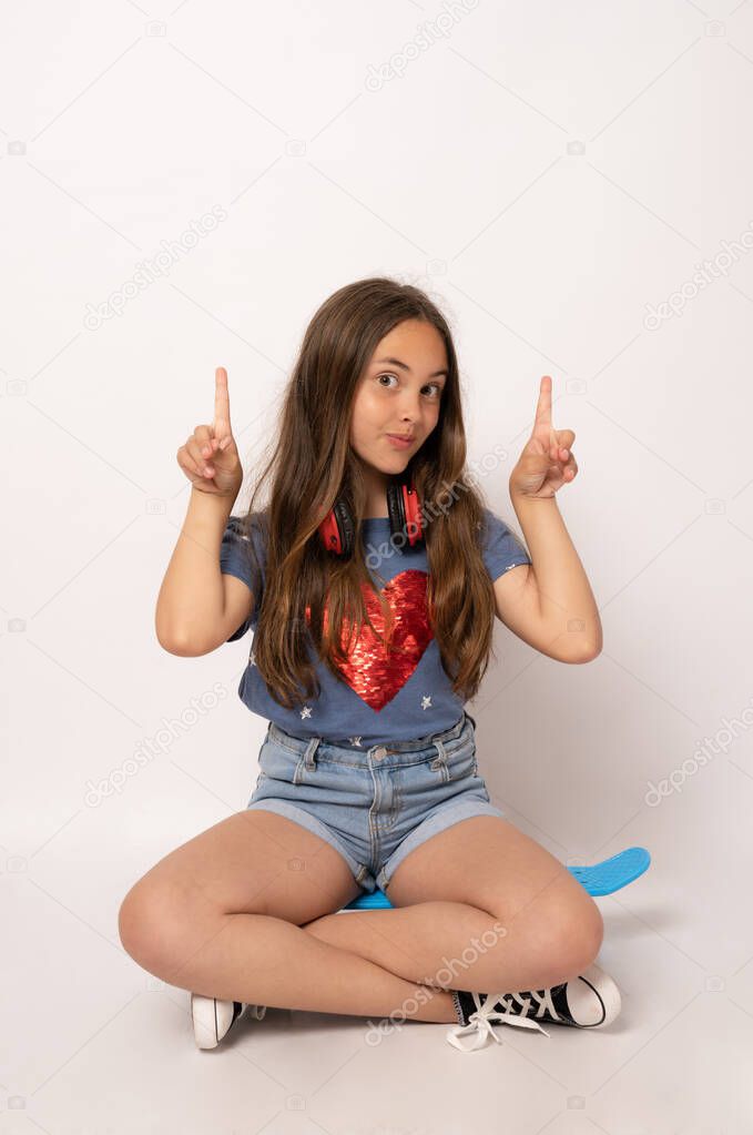 Young brunette girl isolated on white background sitting in a skate and pointing fingers up.