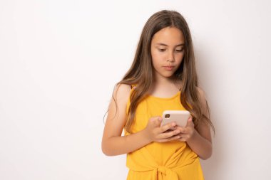 Beyaz arka planda izole edilmiş cep telefonuna bakan gülümseyen esmer bir kızın portresi.