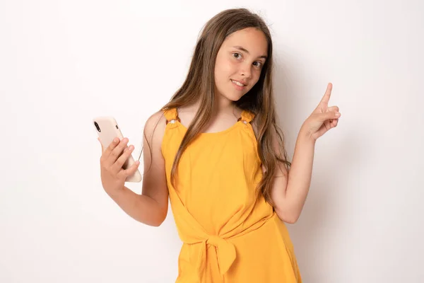 Piękna Brunetka Dziewczyna Smartfonem Wskazując Palec Górę Stojąc Odizolowany Białym — Zdjęcie stockowe