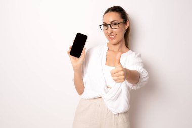 Genç bir iş kadını beyaz arka planda cep telefonu ekranı gösteriyor..