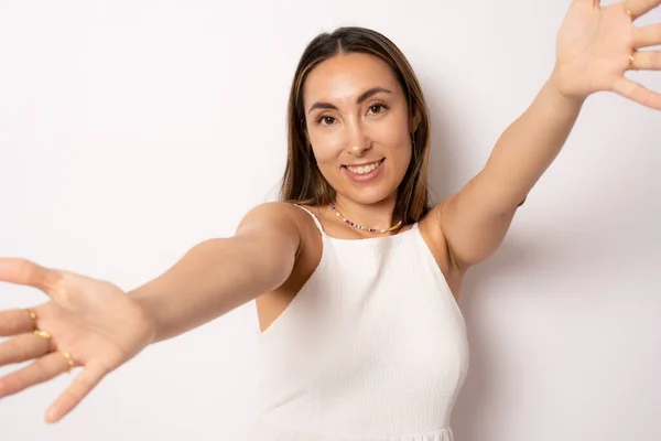 Friendly woman with an open hand ready for hugging standing isolated over white background.