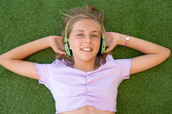 Girl listening to music streaming with headphones in summer on a meadow