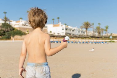 Küçük bir çocuğun gündüz vakti elinde dondurmayla kumsalda yürüdüğünü görüyorum. Yaz tatili kavramı.