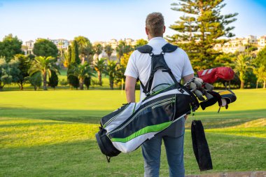 Golf çantasını taşıyan genç ve yakışıklı bir adam..