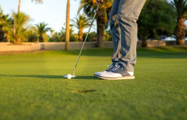 Yeşil çimlerin üzerinde golf topu vurmaya hazır..