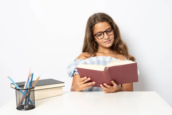 Retrato Una Colegiala Positiva Sentada Detrás Escritorio Leyendo Libro Aislado —  Fotos de Stock