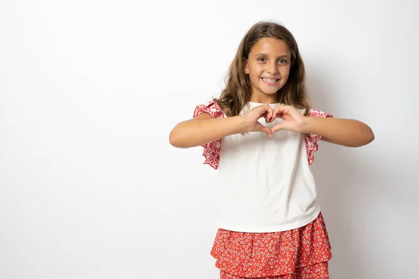 Cute Smiling Brunette Child Girl Heart Figure Fingers Standing Isolated — Stockfoto