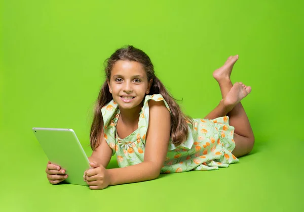 Smiling Girl Lying Floor Using Tablet Computer Isolated Green Background — Zdjęcie stockowe