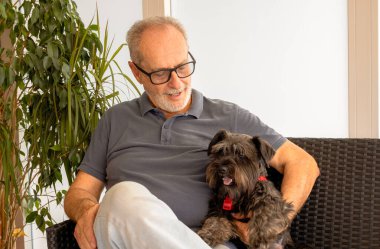 Close-up of a happy, smiling senior man (70 year old Caucasian) holding his cute little dog
