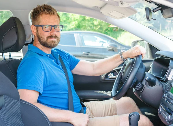 Happy young male driver behind the wheel. The guy in the car. Lifestyle scene in the car dealership