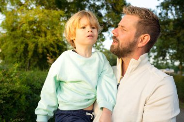 Açık havada babasıyla bağ kuran küçük bir çocuğun portresi.