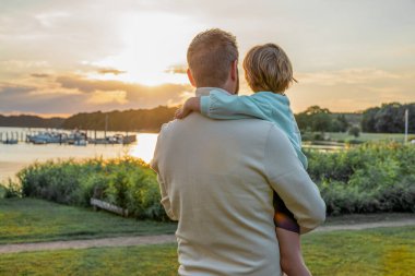 Back view of a shot of a father and his little son bonding together outdoors.