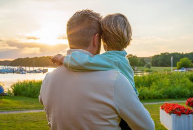 Back view of a shot of a father and his little son bonding together outdoors.