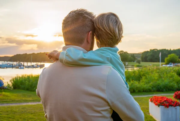 Back view of a shot of a father and his little son bonding together outdoors.