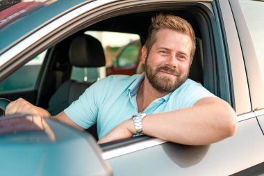 Genç beyaz adam gülümsüyor, mutlu araba kullanıyor..
