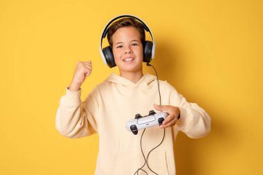 Sarı arka planda tek başına video oyunu oynayan küçük bir çocuk..