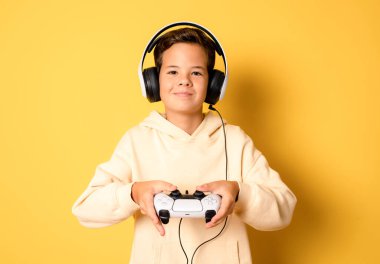 Sarı arka planda tek başına video oyunu oynayan küçük bir çocuk..