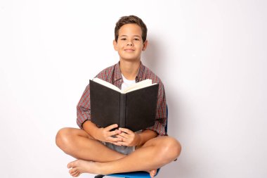 Beyaz arka planda kitabı olan tatlı bir okul çocuğu.