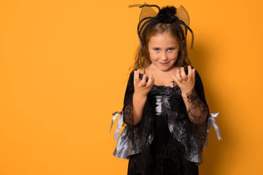 Cadı kostümlü çocuk portresi turuncu arka planda izole edilmiş..