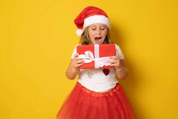 Nettes Kleines Mädchen Mit Weihnachtsmütze Steht Isoliert Über Gelbem Hintergrund — Stockfoto