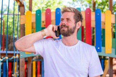 Parkta telefon eden yakışıklı genç adam.