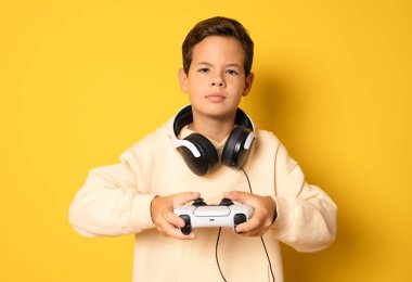 Sarı arka planda tek başına video oyunu oynayan küçük bir çocuk..