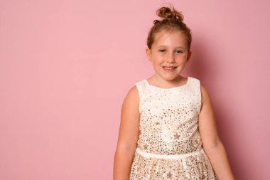 Onun yakın plan portresi. Hoş, sevimli, çekici, sevimli, sevimli, tatlı, neşeli, pembe arka planda izole bir kız çocuğu.