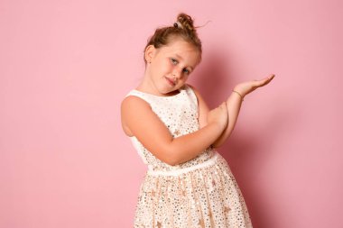 Onun yakın plan portresi güzel, sevimli, tapılası, çekici, sevimli, tatlı, neşeli kız çocuğu pembe arka planda elle izole edilmiş ürünlerini gösteriyor.